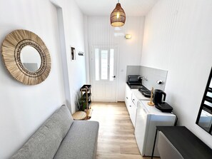 A compact kitchen with a built-in stove, a coffee machine, and a small dining table.