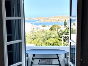 A balcony with a table and chairs, overlooking a body of water with boats and buildings in the distance. - Studio 'Aeolian Blu 8' with Sea View, Wi-Fi and Air Conditioning (Paros)