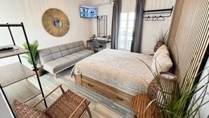 Et moderne soveværelse med seng, sofa, skrivebord og fjernsyn.