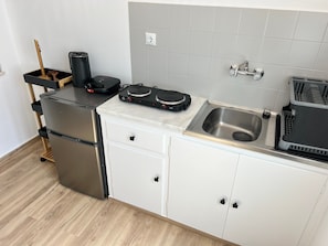 A compact kitchen with a stainless steel refrigerator, a built-in oven, a sink, and a countertop with a dish rack. - Studio 'Aeolian Blu 4' with Sea View, Wi-Fi and Air Conditioning (Paros)