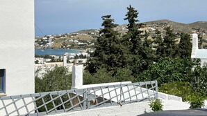 A coastal view with a white building, a clear sky, and a distant town.