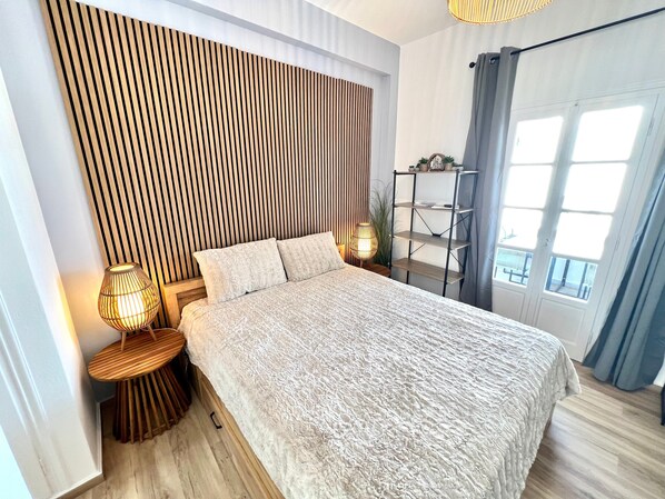 A modern bedroom with a bed, bedside lamps, a wooden slat wall, a metal shelf, and a window with curtains. - Studio 'Aeolian Blu 5' with Sea View, Wi-Fi and Air Conditioning (Paros)