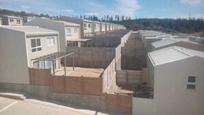 Una hilera de edificios modernos de una sola planta, con techos planos y grandes ventanales, probablemente viviendas.