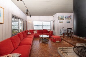 A living room with a red sofa, a round coffee table, and a view of the water through large windows.