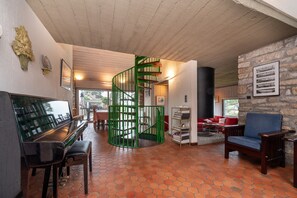 A spiral staircase, a piano, a bookshelf, and a stone wall.