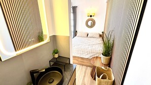 A modern bathroom with a large mirror, a sink, and a small plant. - Studio 'Aeolian Blu 11' with Sea View, Wi-Fi and Air Conditioning (Paros)