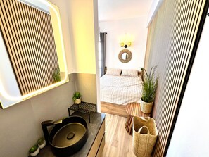 A modern bathroom with a large mirror, a sink, and a small plant. - Studio 'Aeolian Blu 11' with Sea View, Wi-Fi and Air Conditioning (Paros)