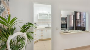 Ett modernt kök med vita skåp, en mikrovågsugn, ett kylskåp och en diskho.