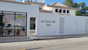 Un edificio blanco con un cartel que dice "La Piscina Del Cielo" y un número de contacto.