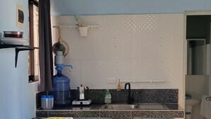 Cocina compacta con lavamanos, encimera y ventilador de techo.