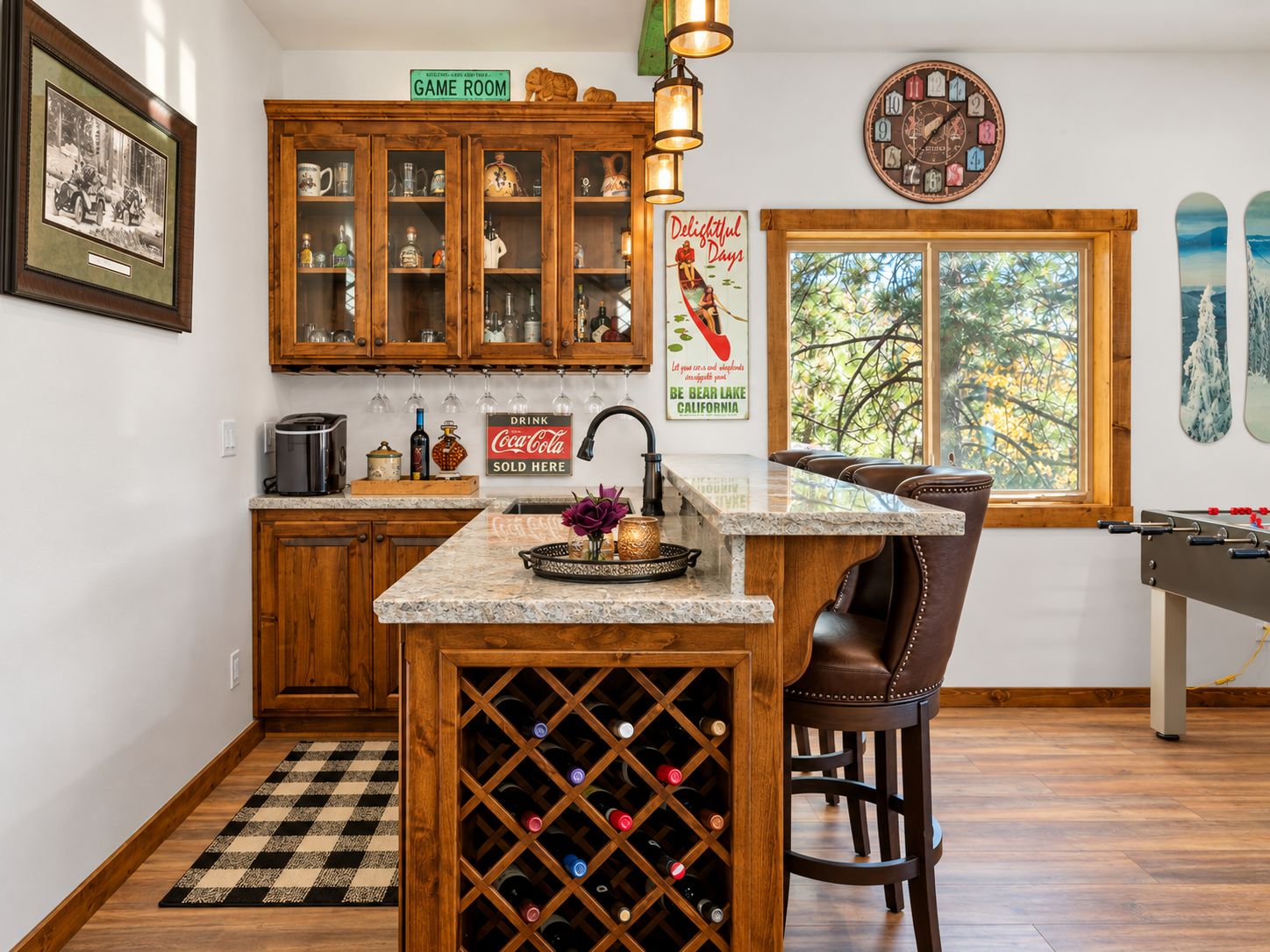 A kitchen with wooden cabinets, a wine rack, a bar stool, and a window with a view of trees.