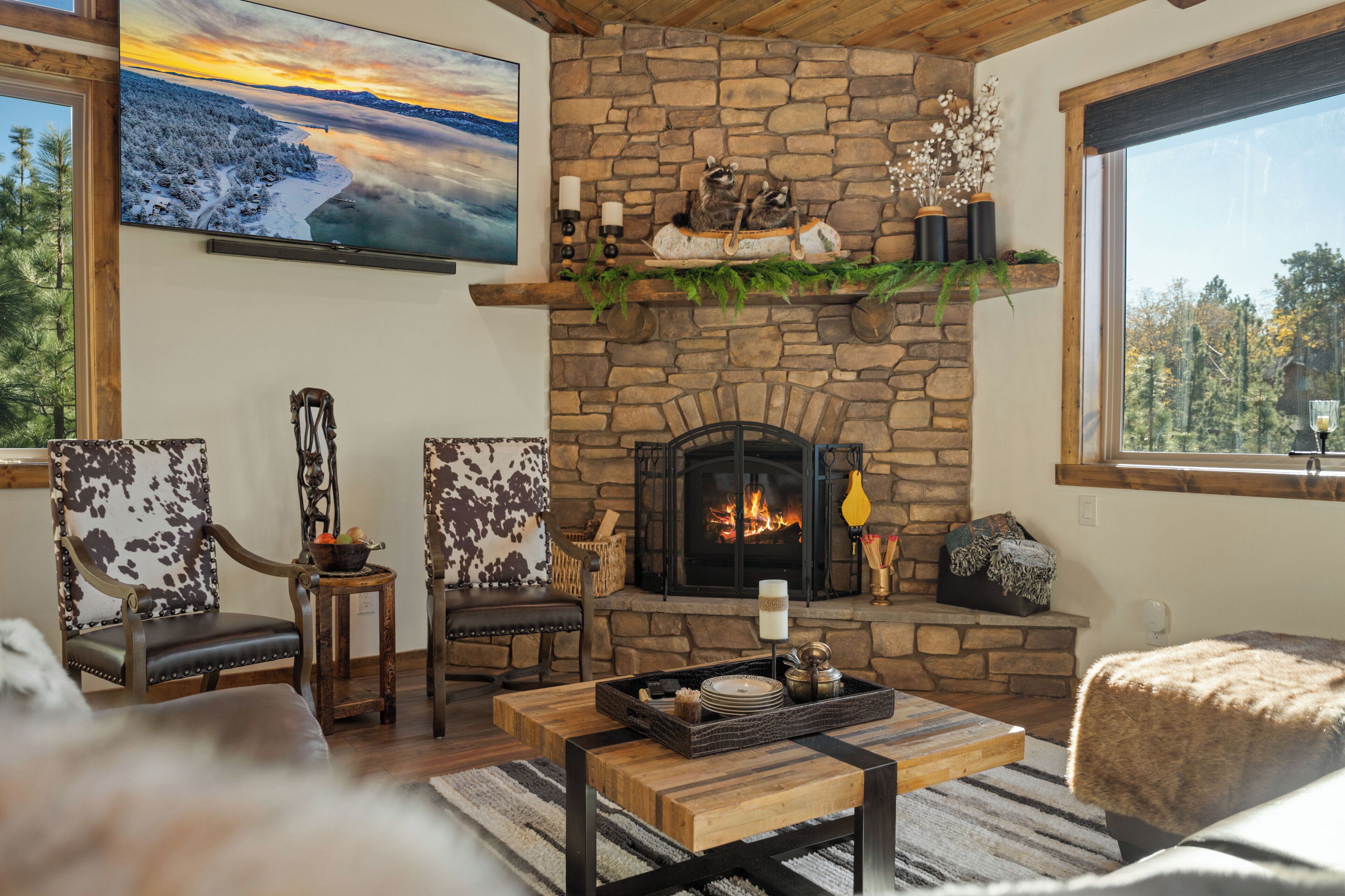 A cozy living room with a stone fireplace, a large painting, and rustic decor.