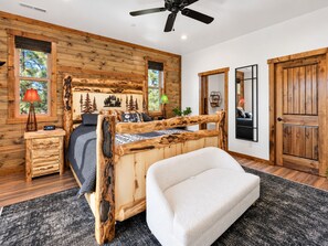 A log cabin-style bedroom with a wooden bed, a bench, and a ceiling fan. - Shem Shack (Big Bear City)