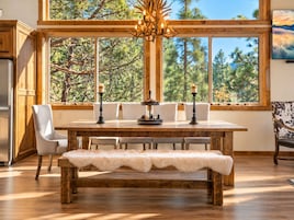 A dining area with a wooden table, chairs, a bench, and a chandelier.