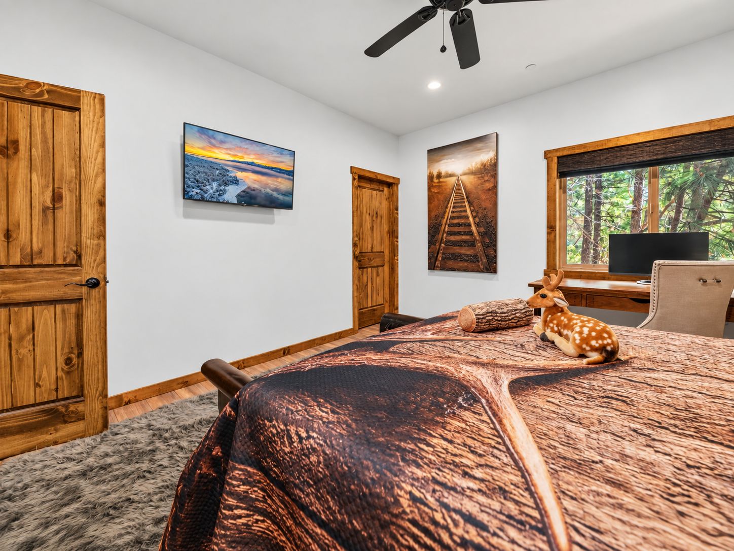 Un dormitorio con una cama grande, puertas de madera, un ventilador de techo y obras de arte en las paredes.