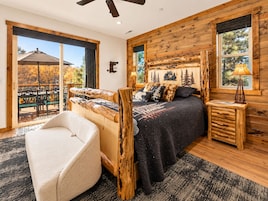 A bedroom with a large bed, wooden headboard, and a view of an outdoor patio.