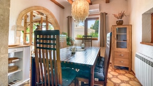 A dining area with a wooden table, chairs, and a hanging light fixture. - Los Caños, Mediterranean Villa, bbq, pool, 5min-beach (Jávea)