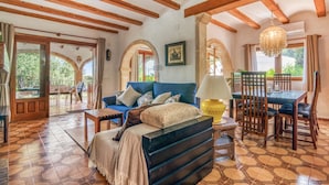 A room with a bed, a sofa, a dining table, chairs, and a chandelier. - Los Caños, Mediterranean Villa, bbq, pool, 5min-beach (Jávea)