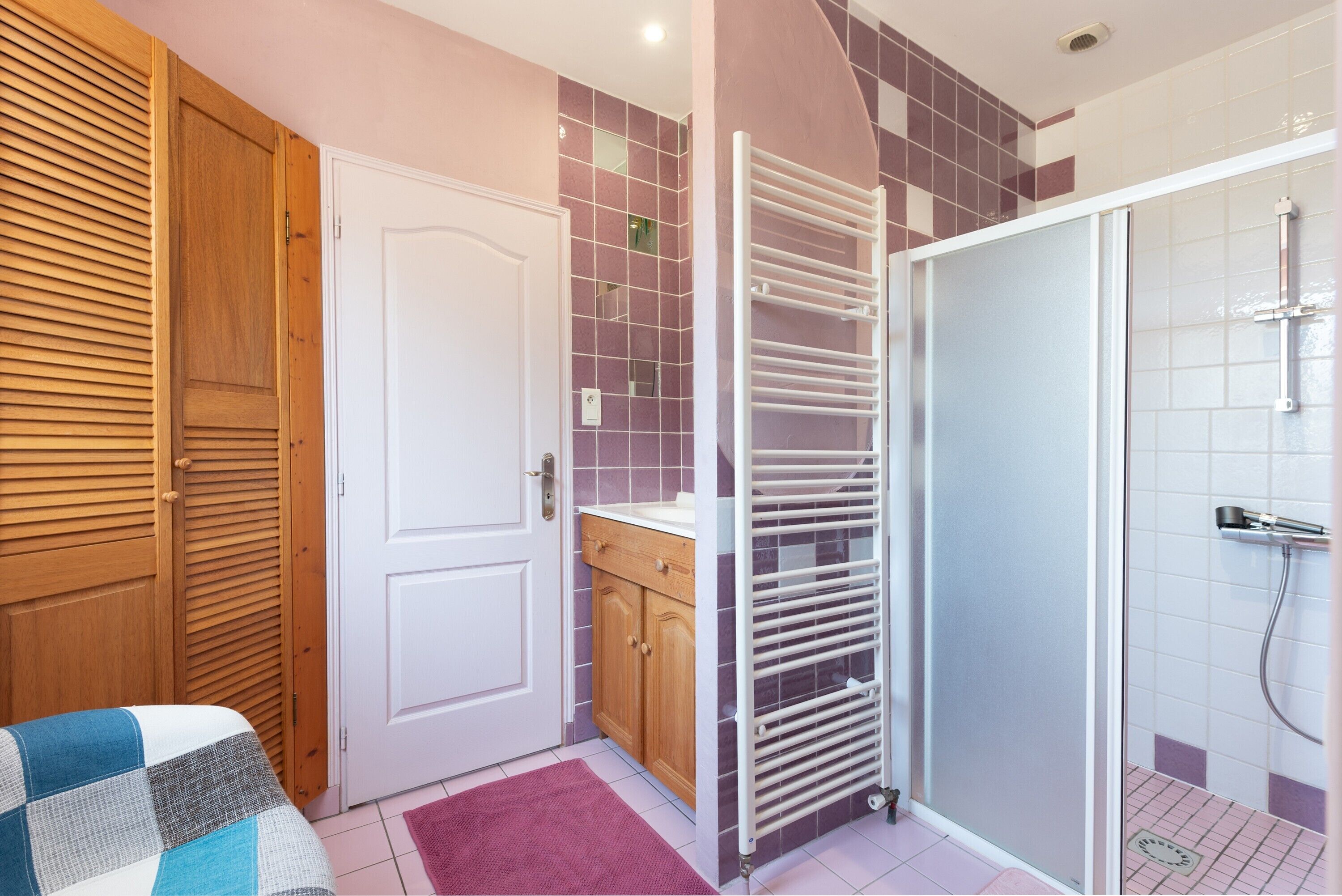 Ein Badezimmer mit Dusche, Handtuchhalter, Holztür und gefliesten Wänden.