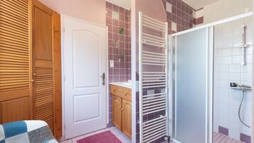 Ein Badezimmer mit Dusche, Handtuchhalter, Holztür und gefliesten Wänden.