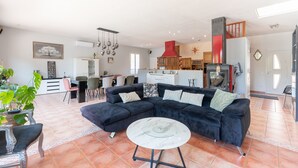 A spacious living area with a sectional sofa, a round coffee table, and a dining area with chairs and a table. - Holiday Home 'Maison Zoé' with Private Pool, Private Terrace and Wi-Fi (Saint-Laurent-de-Neste)
