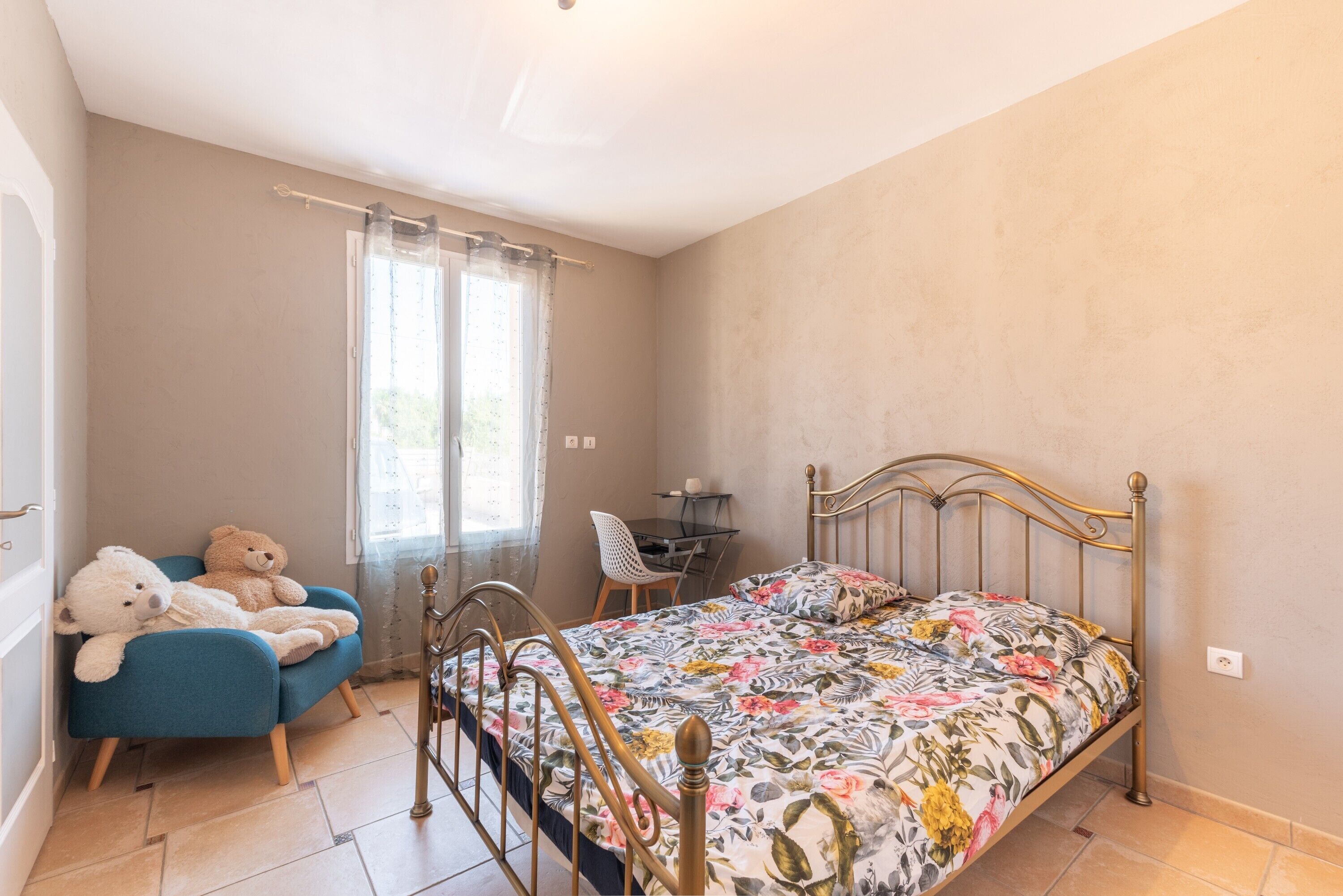 A bedroom with a bed, a desk, a chair, and two teddy bears.