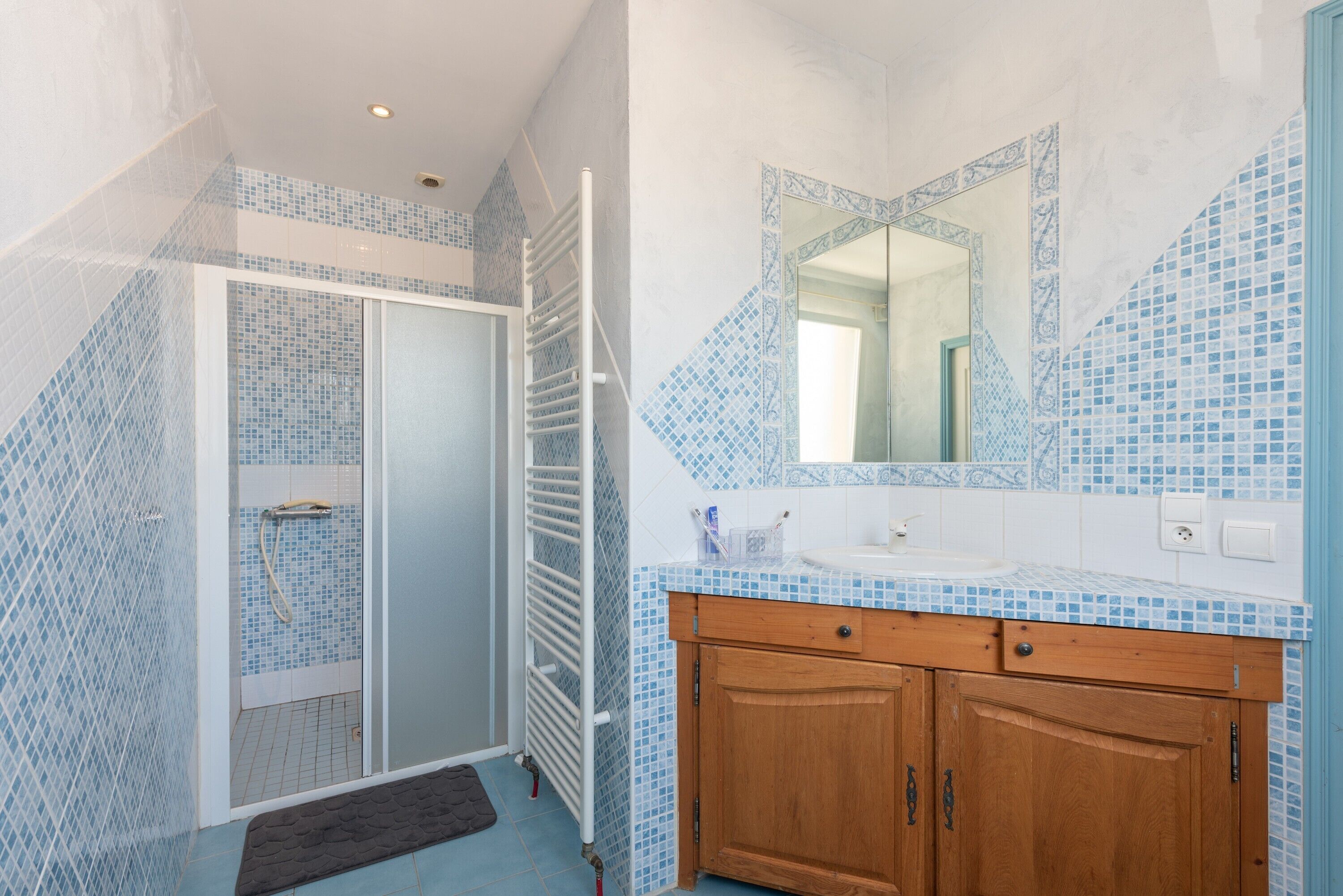 A bathroom with a shower, a sink, and a mirror.