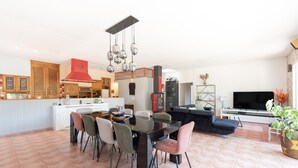 A modern kitchen with a dining area, a living room with a sofa and TV, and a large window. - Holiday Home 'Maison Zoé' with Private Pool, Private Terrace and Wi-Fi (Saint-Laurent-de-Neste)