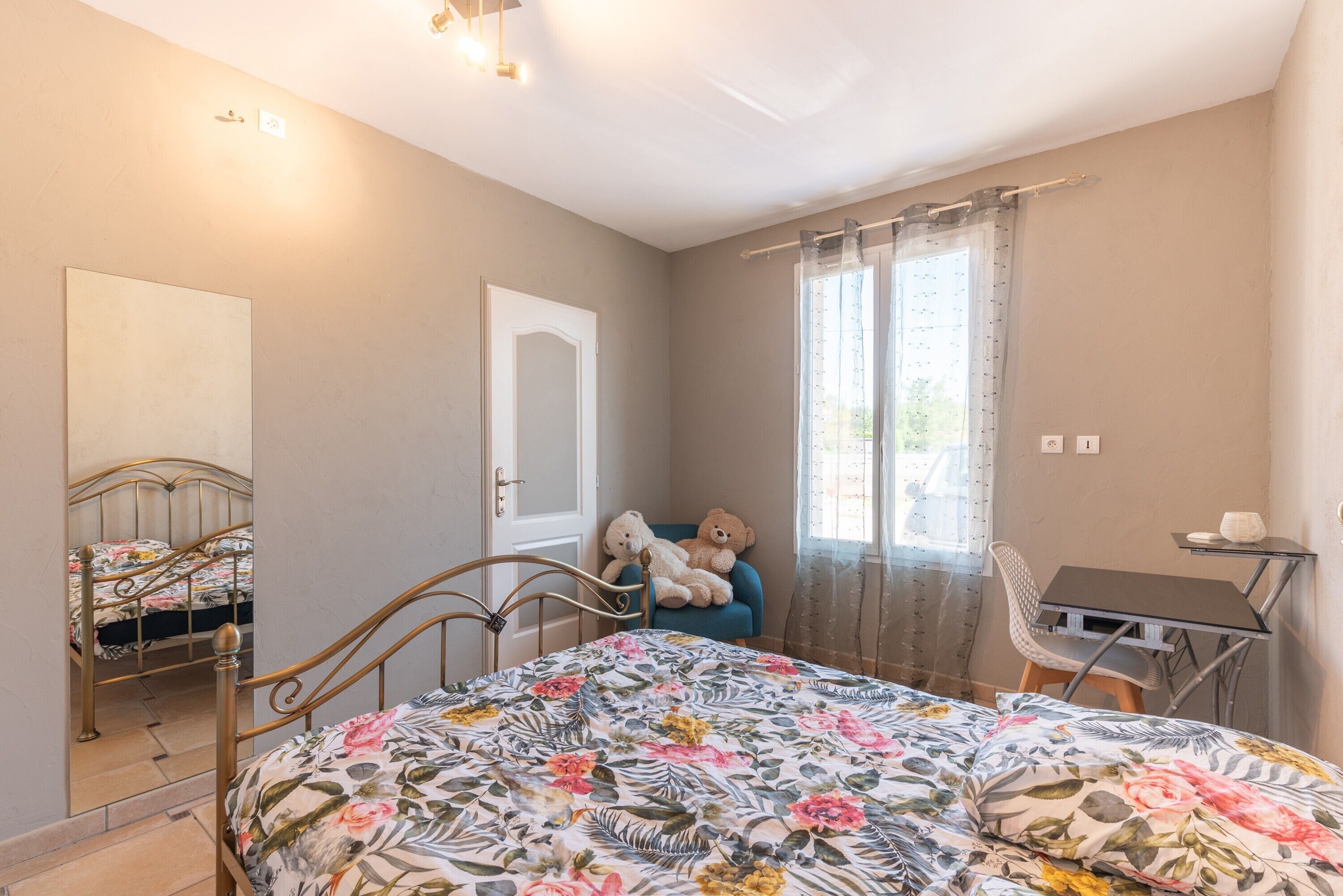 A bedroom with a bed, a chair, a desk, and a teddy bear.