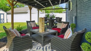 Een terras buiten met rieten meubels, een tafel en een kamerkleed met patroon.