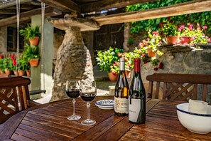 A wooden table with two wine glasses, two bottles of wine, a bowl, and potted plants in a rustic outdoor setting. - Rural House 'Casa Mario' with Mountain Views, Garden and Wi-Fi (Cangas del Narcea)