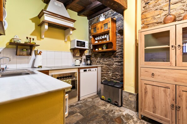 A compact kitchen with a microwave, oven, dishwasher, and wooden cabinets.