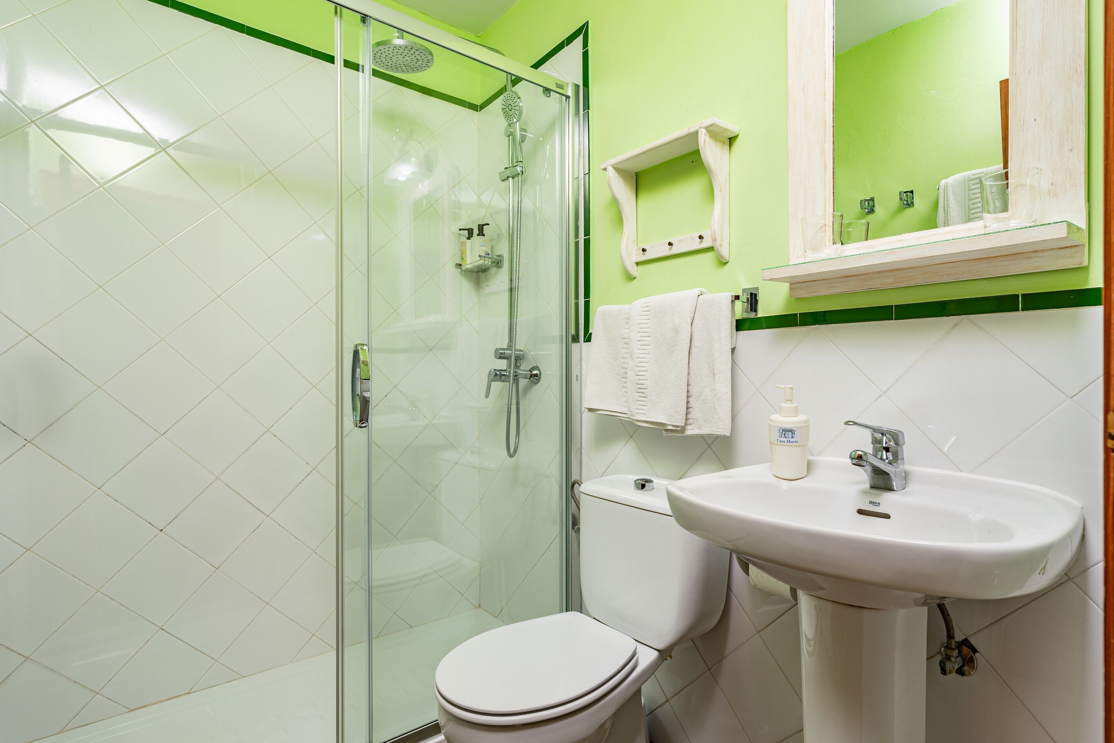 A bathroom with a glass shower enclosure, a white toilet, and a sink with a mirror above it.
