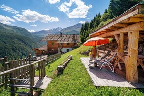 A wooden chalet with a deck, lounge chairs, and a view of mountains. - Holiday Apartment 'Dachwohnung' with Mountain View, Shared Terrace and Wi-Fi (Ultimo)