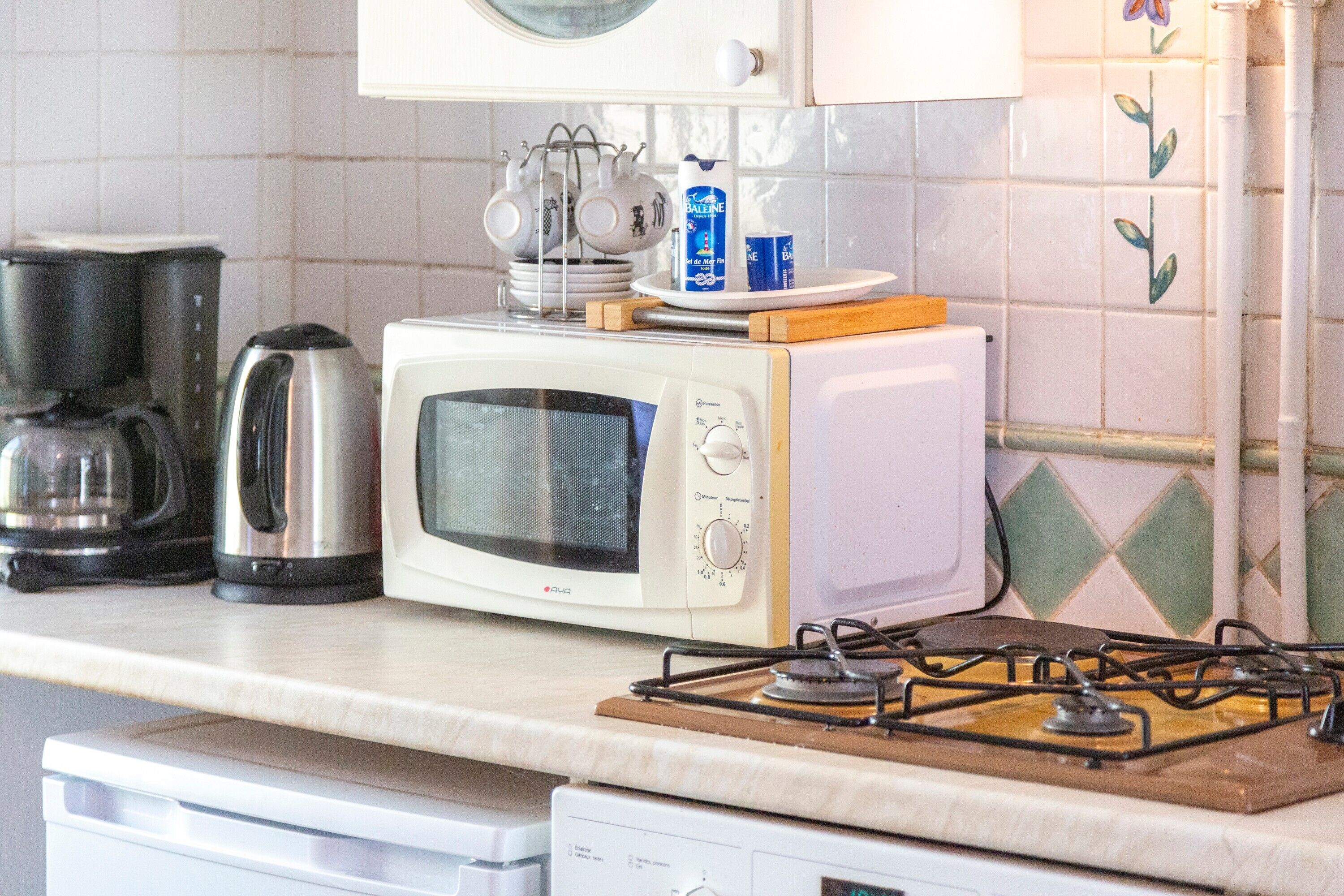 Una cocina con microondas, cafetera y cocina a gas.