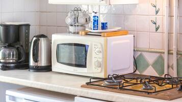 Una cocina con microondas, cafetera y cocina a gas.