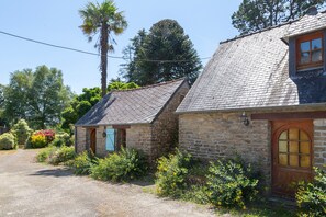 A stone building with a sloped roof, a wooden door, and a window with a wooden frame. - Holiday Home 'Ty Bihan' with Private Terrace and Private Garden (Rosporden)
