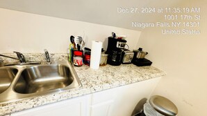 A kitchen with a stainless steel sink, a coffee maker, and various kitchen utensils on the countertop.