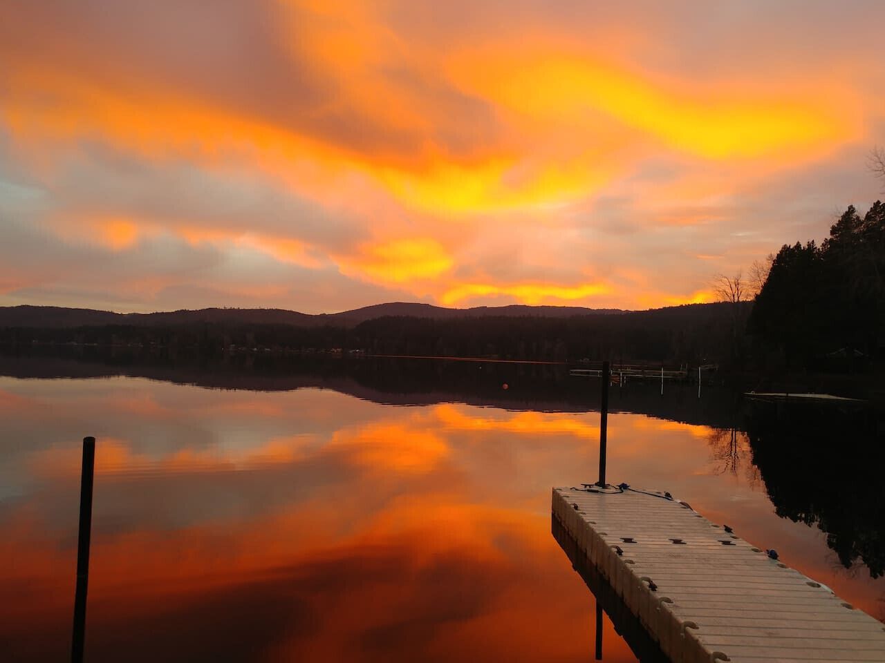 Un lago tranquilo al atardecer con un muelle de madera que se adentra en el agua.