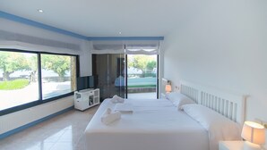 Ein modernes Hotelzimmer mit einem großen Bett, einem Fernseher, einem Schreibtisch und Blick ins Freie.