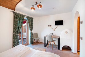 Een slaapkamer met een bed, bureau, stoel, open haard en een televisie.