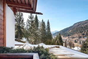 Ein Holzbalkon mit Blick auf eine verschneite Landschaft und Kiefern.