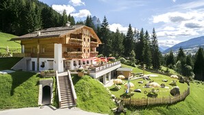 Un chalet doté d’un balcon, d’un escalier et d’un jardin orné de statues de moutons.