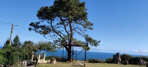 A tree with a wooden platform, a clear sky, and a distant view of the sea. - Villa 'Quintes' with Sea View, Private Terrace and Wi-Fi (Villaviciosa)
