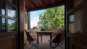 An open patio with a table and chairs, a stone wall, and potted plants. - Villa 'Quintes' with Sea View, Private Terrace and Wi-Fi (Villaviciosa)