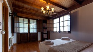 A bedroom with wooden floors, a bed with white linens, a chandelier, and large windows. - Villa 'Quintes' with Sea View, Private Terrace and Wi-Fi (Villaviciosa)