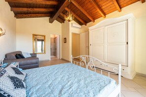 A bedroom with a bed, a sofa, a wardrobe, and a chandelier. - Villa 'Pretziosa' with Private Pool, Wi-Fi and Air Conditioning (Castiadas)