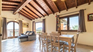 A spacious living area with a dining table, chairs, a sofa, and a balcony with a view of the mountains. - Villa 'Pretziosa' with Private Pool, Wi-Fi and Air Conditioning (Castiadas)