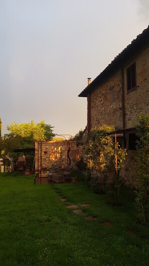 Un bâtiment en pierre doté d’un jardin, d’une tonnelle en bois et d’un four en briques.