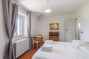 Une chambre à coucher comprenant un lit, un bureau, une chaise, un radiateur, un miroir et une porte.
